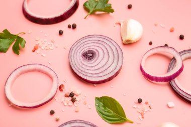 Pembe arka planda taze soğan dilimleri ve baharatlar, yakın plan.