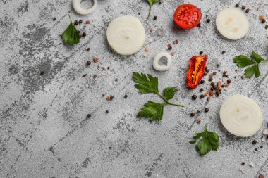 Gri zemin üzerinde taze soğan dilimleri ve baharatlar.