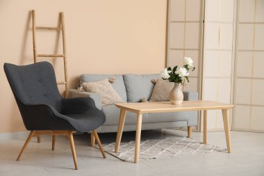 Koltuklu koltuk, tuvalet perdesi ve bej duvarın yanındaki kahve masası.