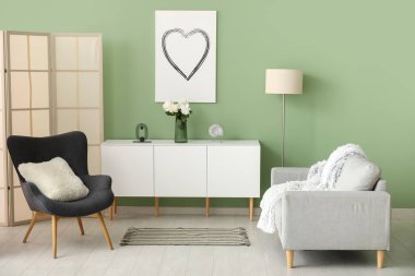 Yeşil duvarın yanındaki koltuklar, lamba ve giyinme masası.