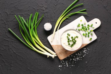 Siyah arka planda dilimlenmiş yeşil soğanlı lezzetli ekşi krema.