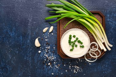 Mavi arka planda soğan ve soğanlı bir kase lezzetli ekşi krema.