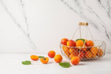 Beyaz masada taze kayısı sepeti.