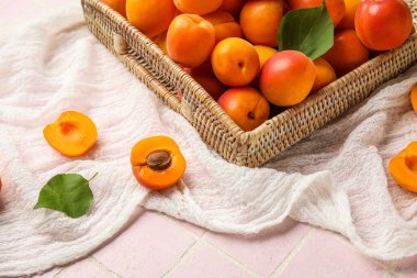 Pembe fayans zemininde taze kayısıları olan bir etiket kutusu.