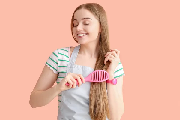 ピンクの背景に女性の美容師ブラッシング髪 — ストック写真