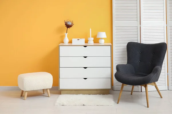 Ciemnoszary Fotel Ekranem Opatrunkowym Komodą Puszystym Dywanem Przy Pomarańczowej Ścianie — Zdjęcie stockowe