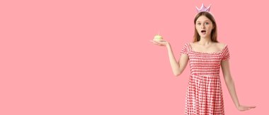 Pembe arka planda doğum günü pastası olan, mesaj atmak için yeri olan şaşırmış genç bir kadın.