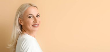 Bej arkaplanlı çekici, olgun, sarışın kadın. Metin için yeri var.