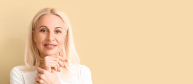 Bej arkaplanlı çekici, olgun, sarışın kadın. Metin için yeri var.