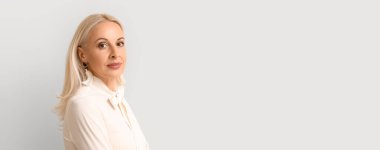 Açık arkaplanda mesaj için yeri olan oldukça olgun sarışın bir kadın.