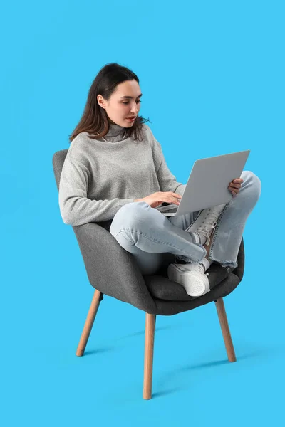Young Woman Using Laptop Black Armchair Blue Background — Fotografia de Stock