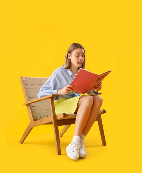 Junge Frau Liest Magazin Holzsessel Auf Gelbem Hintergrund — Stockfoto