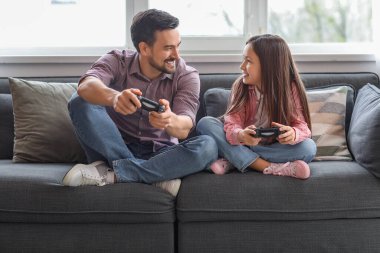 Babası ve küçük kızı evde video oyunu oynuyorlar.