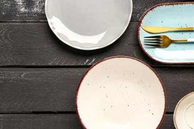 Temiz tabaklar ve siyah ahşap masa üzerindeki çatal bıçak takımlarıyla kompozisyon