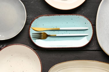 Temiz tabaklar ve siyah ahşap masa üzerindeki çatal bıçak takımlarıyla kompozisyon