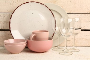 Bej rengi ahşap duvarın yanındaki masada farklı tabaklar var.