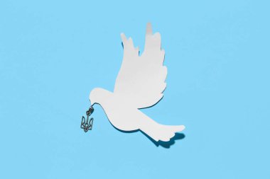 Mavi arka planda Ukrayna armalı kolye ve kağıt güvercin.