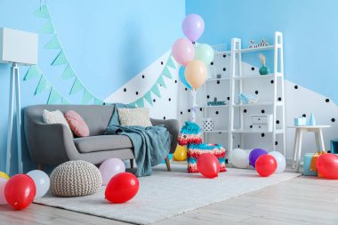 Doğum günü için dekore edilmiş oturma odasının içinde balonlar, pinyatalar ve çelenkler var.