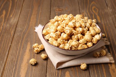 Tahta arka planda gevrek patlamış mısır kasesi.