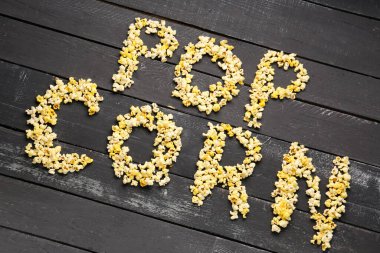 Koyu ahşap arkaplanda POP CORN metni