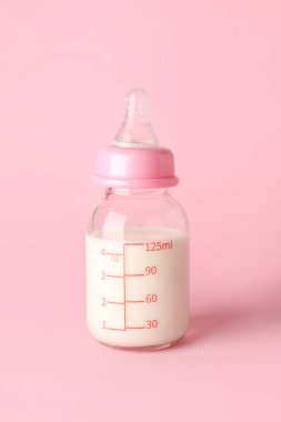 Pembe arka planda bebek için bir şişe süt