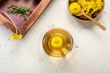 Beyaz arka planda çiçekli bir bardak sağlıklı karahindiba çayı ve kase.