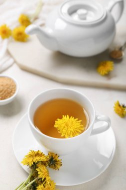 Beyaz arka planda bir fincan sağlıklı karahindiba çayı ve çaydanlık.