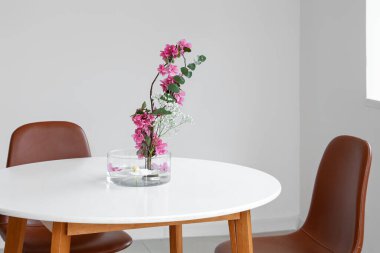 Aydınlık odada yemek masasında güzel bir ikebana