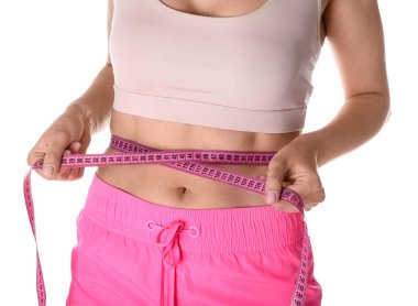 Beyaz arka plan kasette ölçme ile genç bir kadın. Diyet kavramı