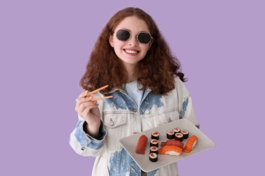 Leylak arka planında suşi ve yemek çubuğu olan genç bir kadın.