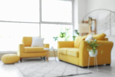 Sarı koltuklu, büyük pencereli, bulanık manzaralı, aydınlık oturma odasının içi.