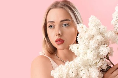 Pembe arka planda leylak çiçekleri olan genç kadın, yakın plan.