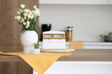 Mutfaktaki masada gül ve sulu vazo.