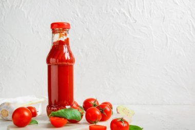 Cam ketçap şişesi ve beyaz arka planda domatesli tahta.