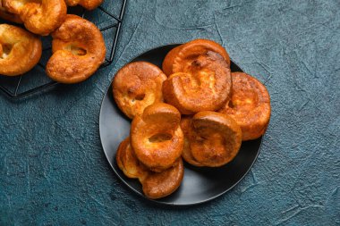 Mavi arka planda lezzetli Yorkshire pudingi olan tabak.
