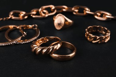 Güzel zincir bilezik ve siyah zemin üzerinde yüzükler