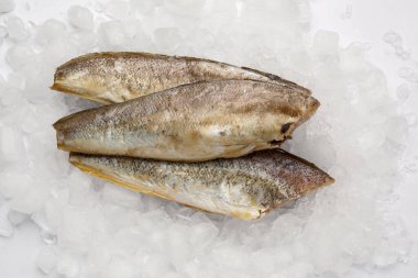 Beyaz zemin üzerinde buz küpleri olan çiğ morina balığı