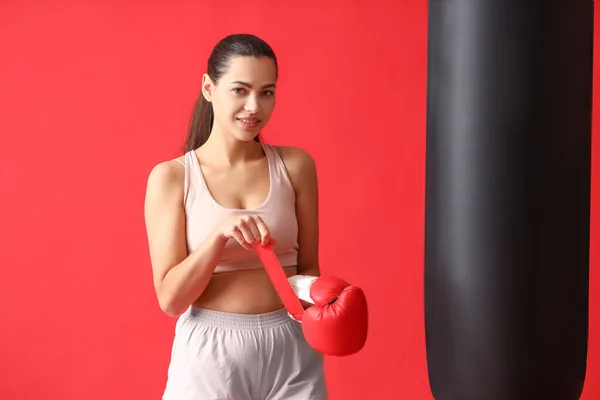 Молодая Женщина Надевает Боксерскую Перчатку Боксерскую Грушу Красный Фон — стоковое фото