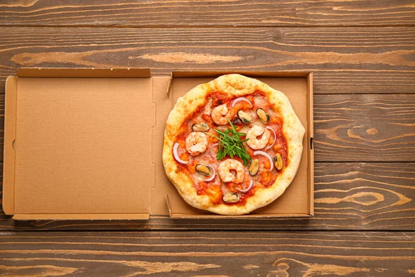 Scatola Cartone Con Gustosa Pizza Frutti Mare Sfondo Legno — Foto Stock