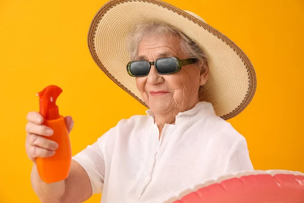 オレンジの背景に日焼け止めクリームを持つシニア女性 クローズアップ — ストック写真