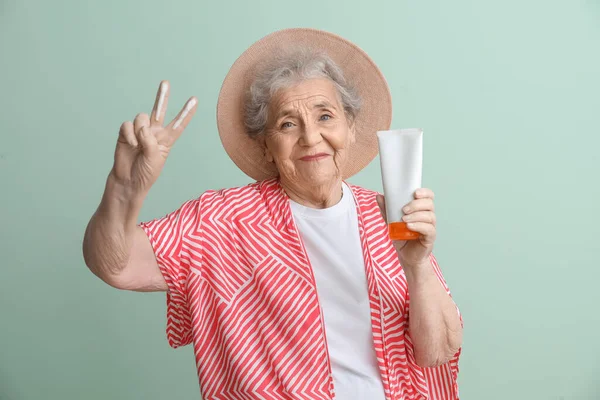 Seniorin Mit Sonnencreme Zeigt Siegesgeste Auf Grünem Hintergrund — Stockfoto