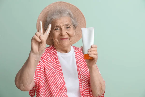 Seniorin Mit Sonnencreme Zeigt Siegesgeste Auf Grünem Hintergrund — Stockfoto