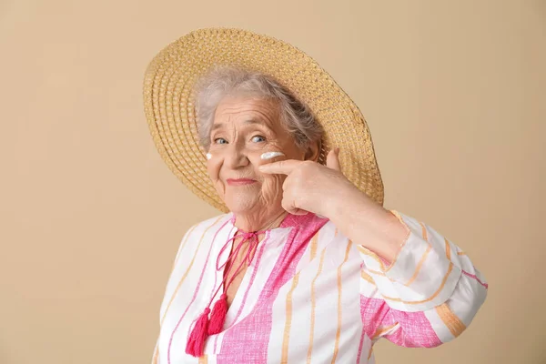 Ηλικιωμένη Γυναίκα Αντηλιακή Κρέμα Στο Πρόσωπό Της Μπεζ Φόντο — Φωτογραφία Αρχείου