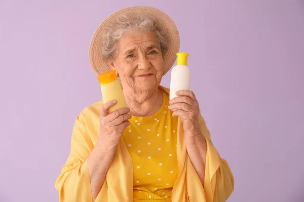 Старша Жінка Пляшками Сонцезахисного Крему Бузковому Фоні — стокове фото