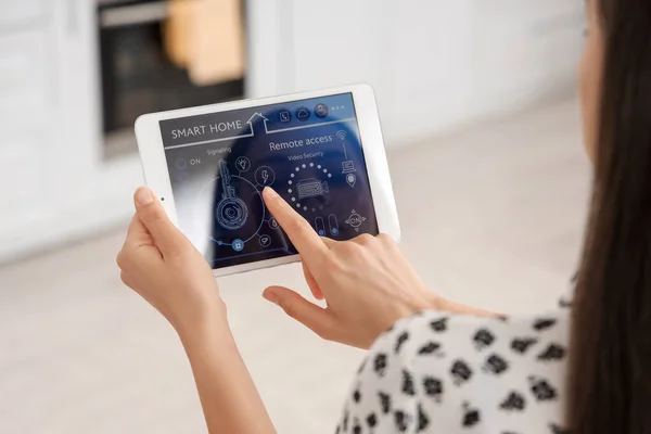 stock image Young woman using smart home security system control panel in kitchen, closeup