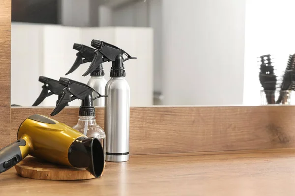 stock image Hairdryer and bottles of spray on table in beauty salon