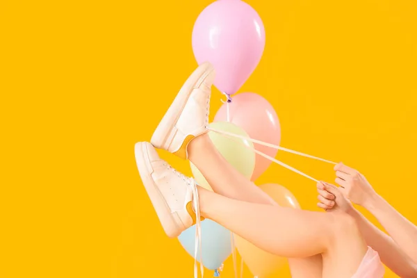 Mujer Joven Atando Cordones Zapatos Con Globos Sobre Fondo Amarillo — Foto de Stock