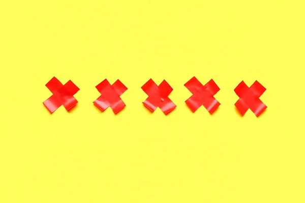 黄色の背景に接着テープで作られた赤い十字 — ストック写真