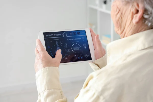 Senior woman with smart home security system control panel, closeup