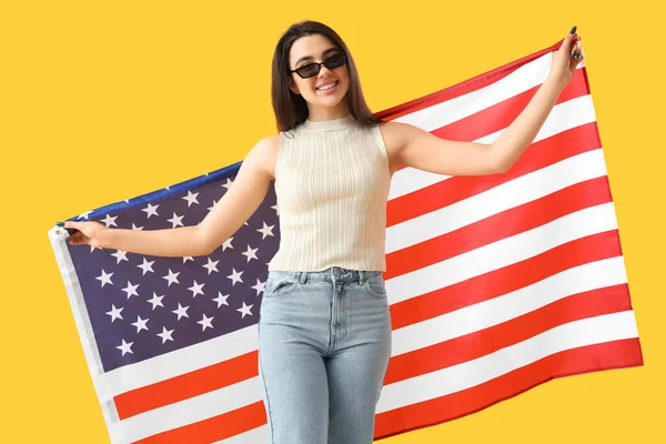 黄色の背景にアメリカの旗を持つ若い女性 — ストック写真